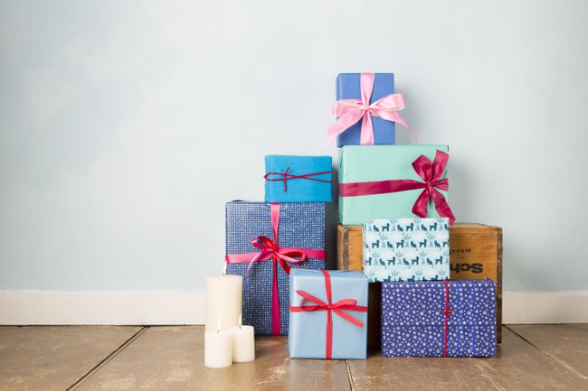 Candles and stack of wrapped christmas gifts on wooden floor