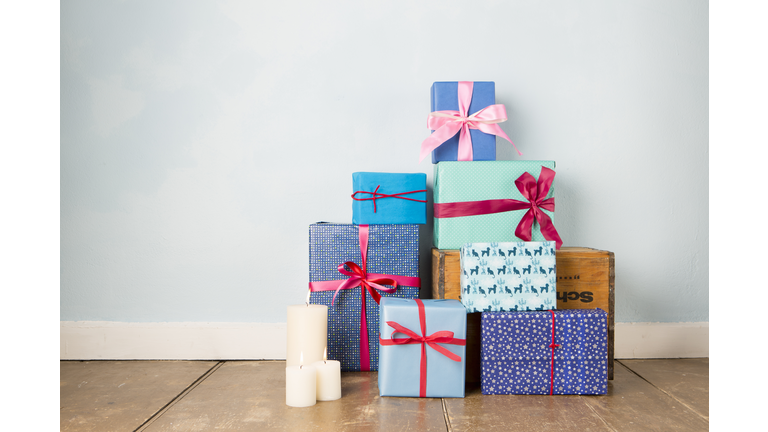Candles and stack of wrapped christmas gifts on wooden floor