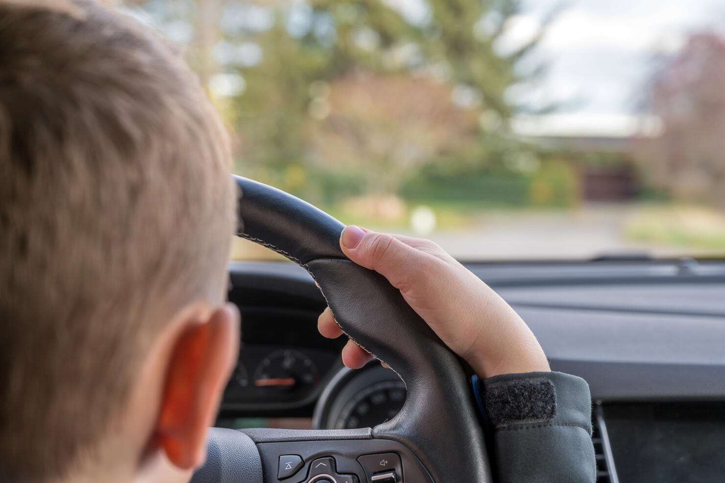 Child drives daddy's car on a street