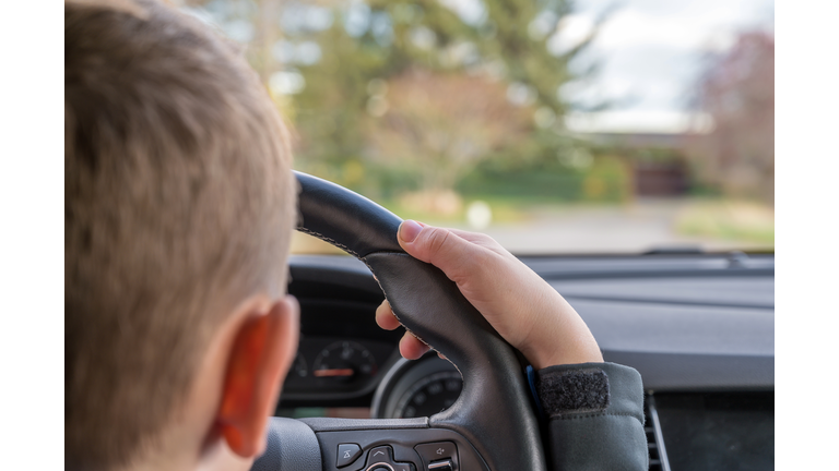 Child drives daddy's car on a street