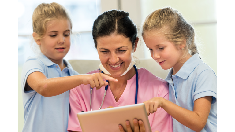 Looking at the tablet with her little patients