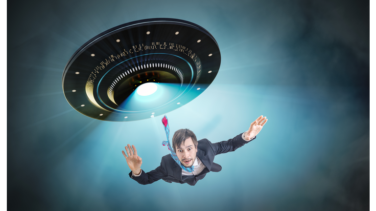 Alien abduction concept. Young man is abducted by UFO.