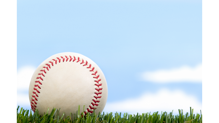 New Baseball in Grass against blue sky