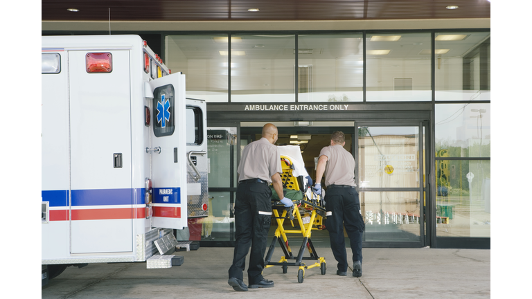Paramedics taking patient on stretcher from ambulance to hospital