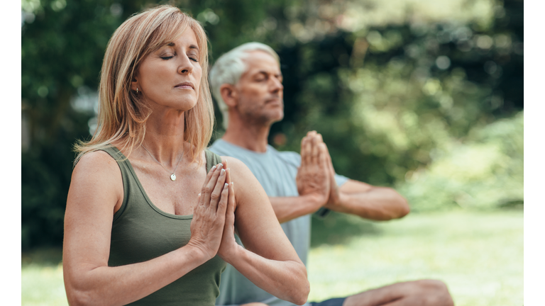 Mature couple meditating together during yoga practice outside
