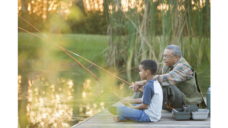 Grandfather and grandson fishing on pier