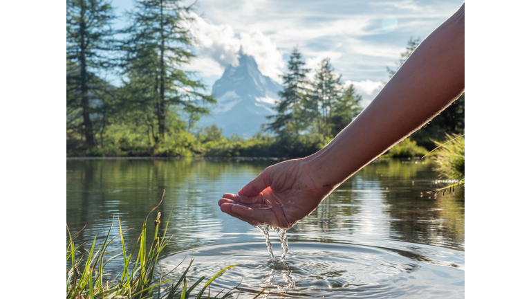 Hands scooping water from alpine lake