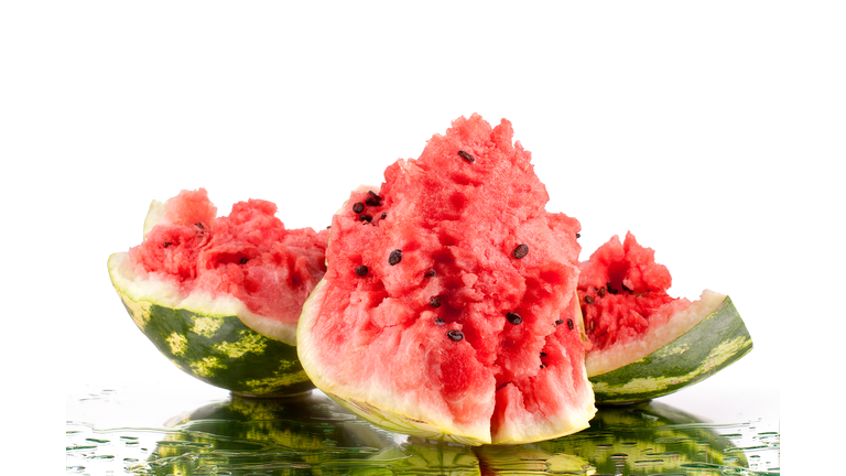 Watermelon pieces on white mirror background in water drops isolated close up