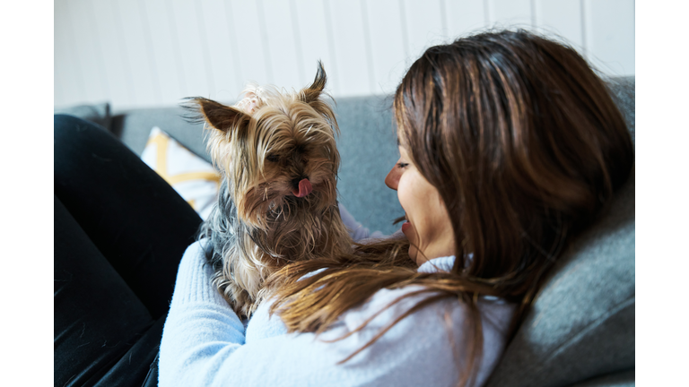 Woman strocking her dog while laying on couch.