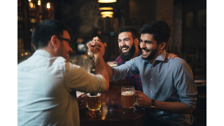 Men watching football in bar and drink beer