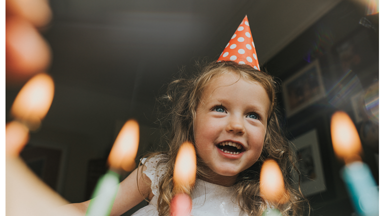 Cute little Girl above a Birthday cake, about to blow out the candles.