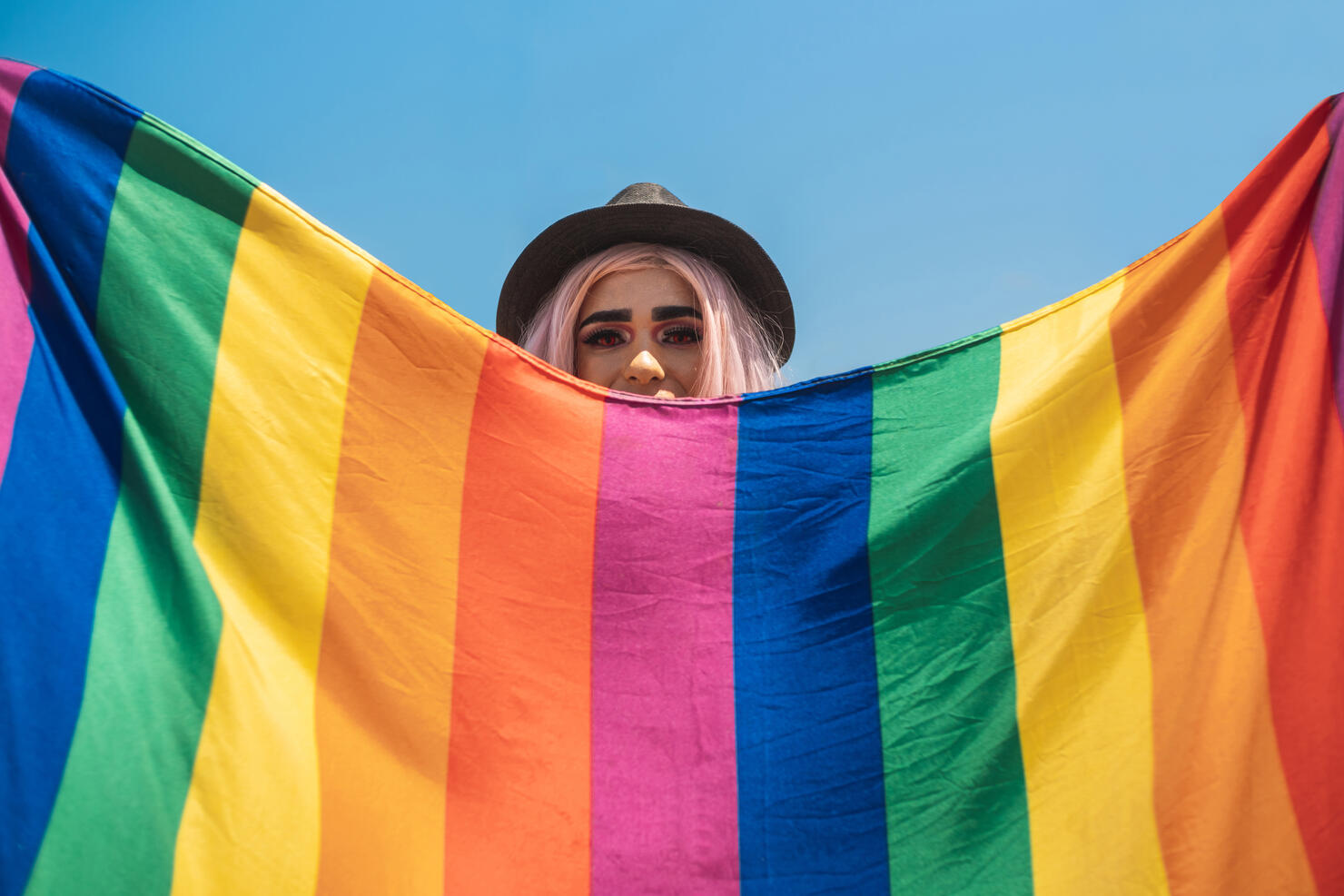 Drag queen hiding behind the rainbow flag