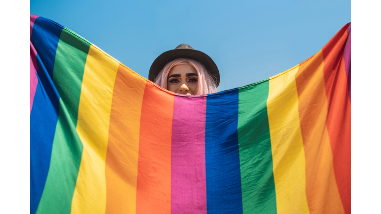 Drag queen hiding behind the rainbow flag