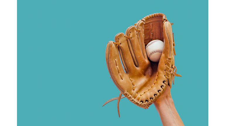 Hand In A Leather Baseball Glove Catches A White Ball In Defocus On A Red Background