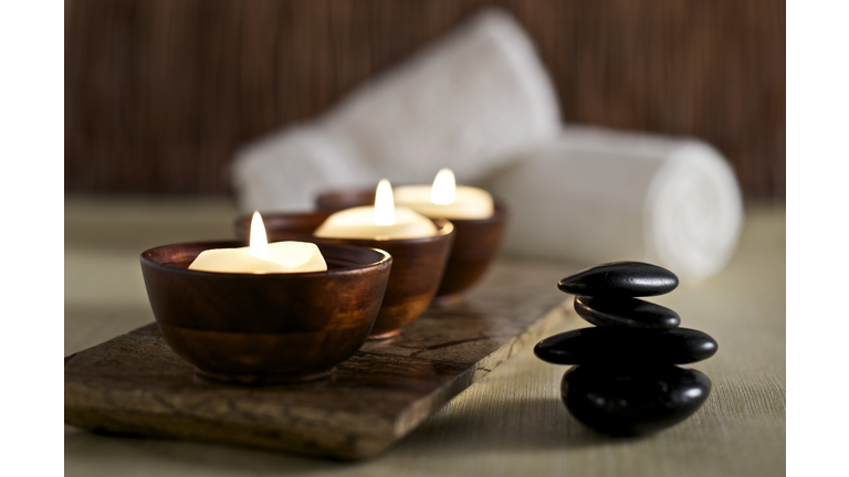 Lit candles and black massage stones in Zen spa