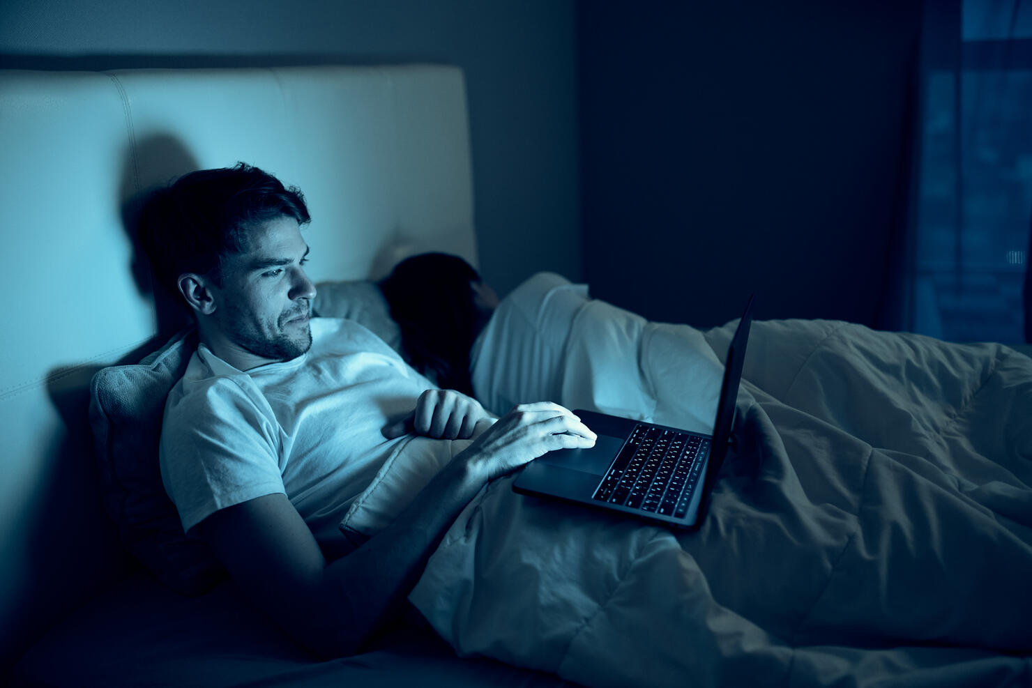 A man and a woman sleep in the same bed, and a man browses adult sites on the Internet at night.
