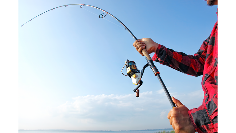 Fisherman standing in a lake and catching the fish with fishing rod