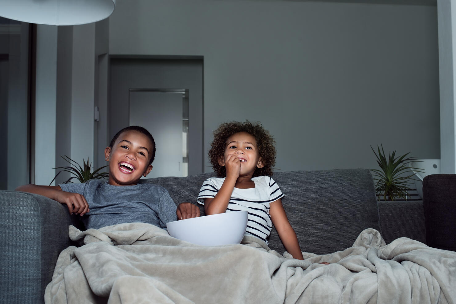 Happy siblings having popcorn while watching TV
