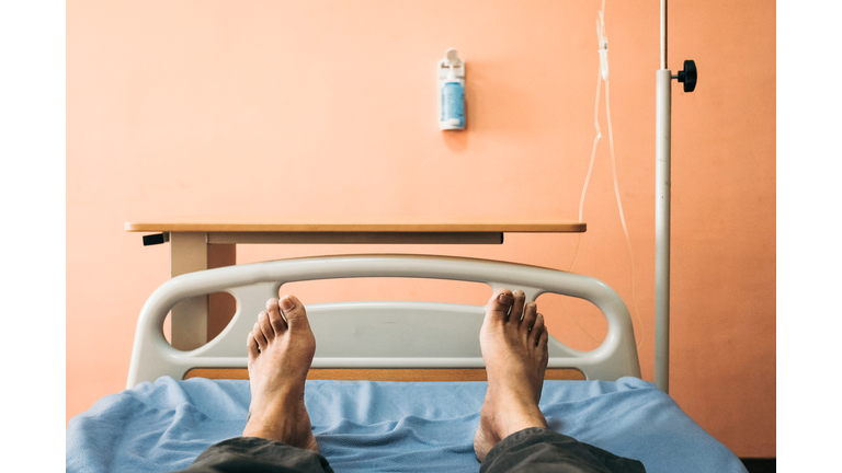 Low Section Of Man Relaxing On Bed At Hospital