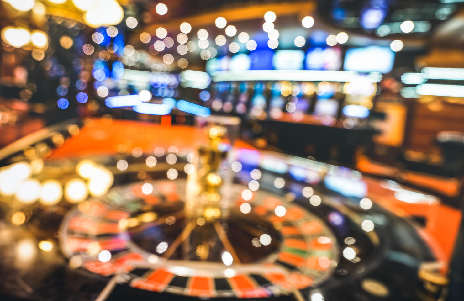 Blurred defocused background of roulette at casino saloon - Gambling concept with unfocused game room with video poker slot machines and multicolored blurry lights