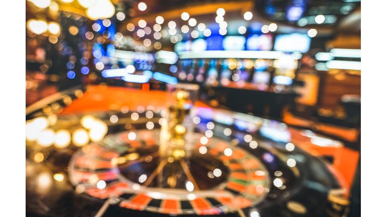 Blurred defocused background of roulette at casino saloon - Gambling concept with unfocused game room with video poker slot machines and multicolored blurry lights