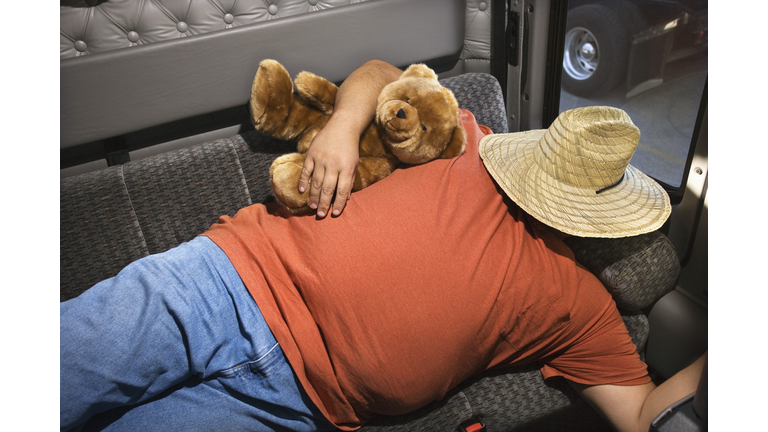 Man sleeping in back of truck with teddy bear