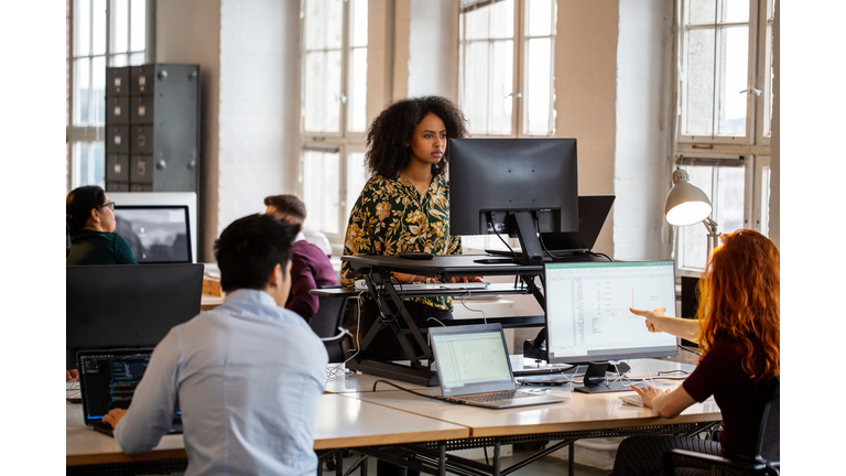 Woman working on computer at ergonomic standing desk in office