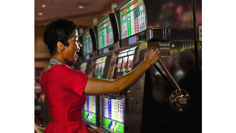 Mixed race woman playing slot machines in casino