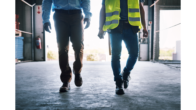 Shot of two unrecognisable builders walking through a construction site