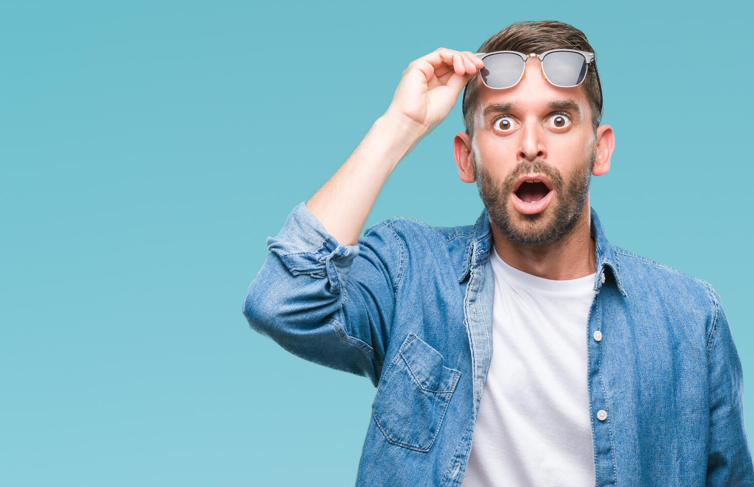 Young handsome man wearing sunglasses over isolated background afraid and shocked with surprise expression, fear and excited face.