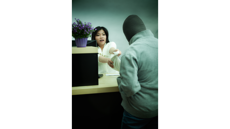 Bank Robbery in Progress with Asian Bank Teller at Retail Bank Counter