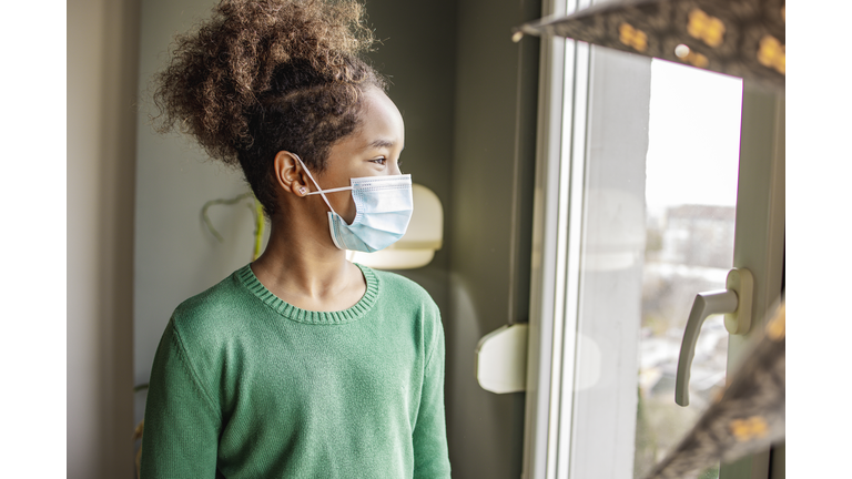 African American girl with face mask by the window