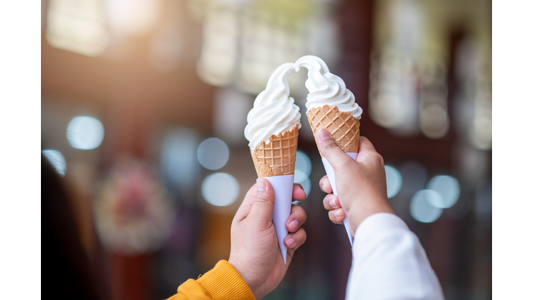 Young lovers are eating ice cream in their hands and raising them.