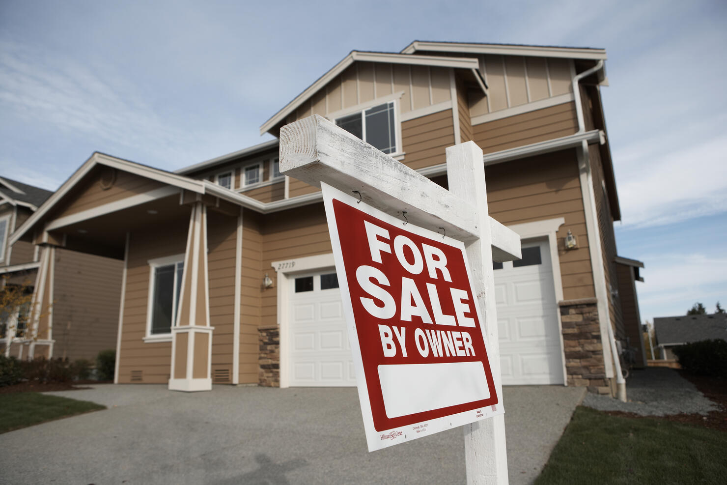 'For Sale' sign in front of house (focus on sign)