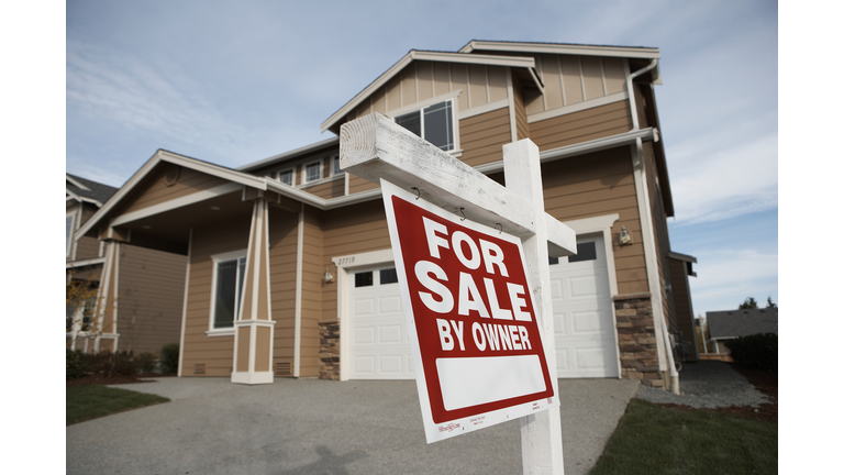 'For Sale' sign in front of house (focus on sign)
