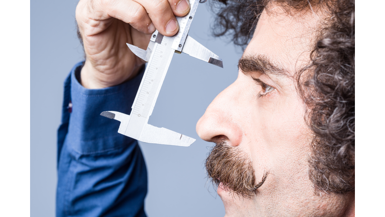 Close Up Portrait Of Adult Man Measuring His Nose