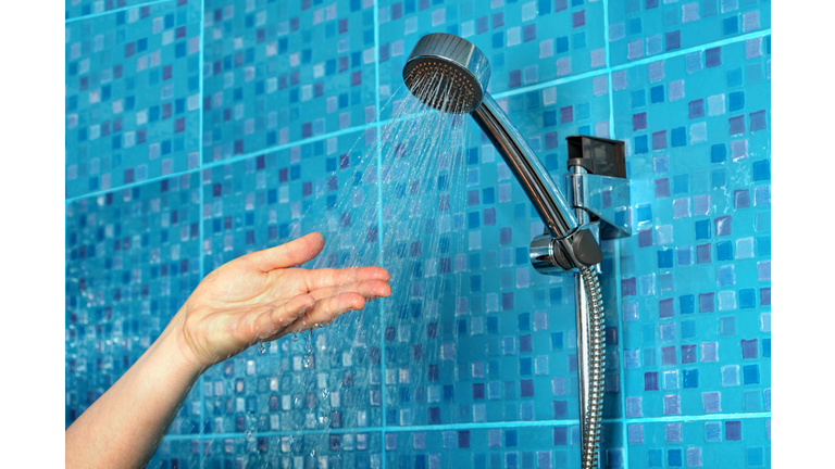 Cropped Hand Of Woman Under Shower Head At Bathroom