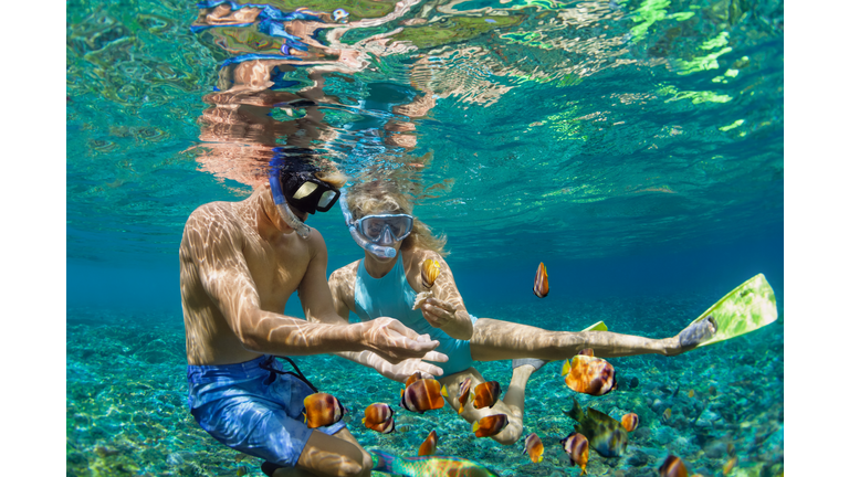 Young couple in snorkeling mask dive underwater in tropical sea