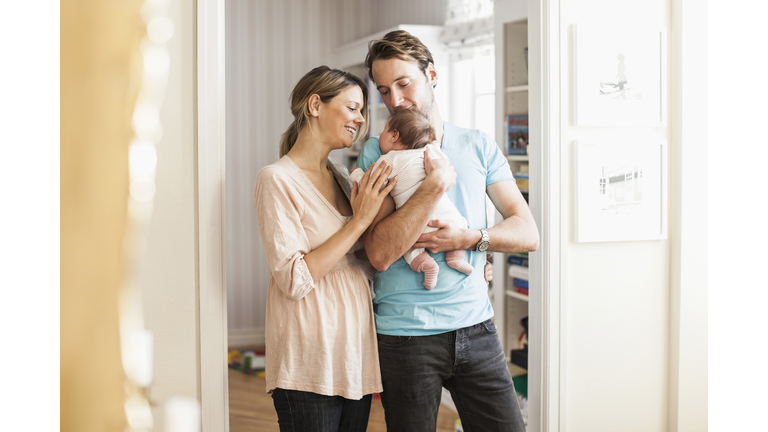 Mid adult coupe playing with baby girl at doorway