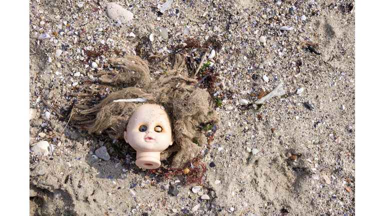 Head of children's doll on the beach trash