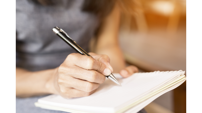 Women holding a pens writing a notebook. Recording concept