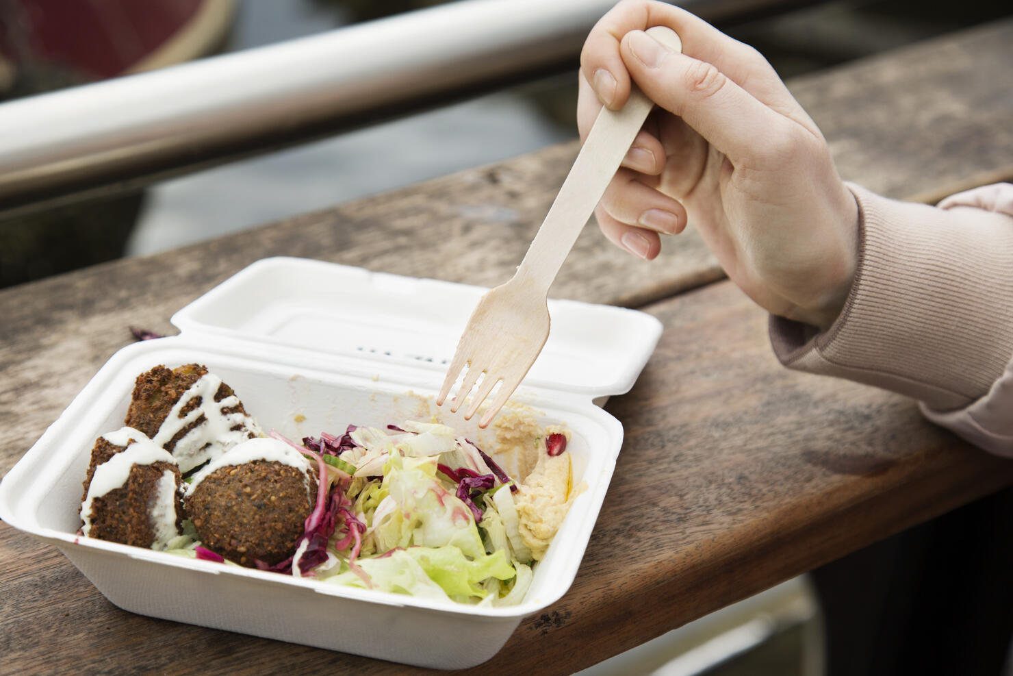 Close up of healthy food in take away box, hand holding fork at urban market.