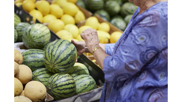 Woman choosing watermelon in shop