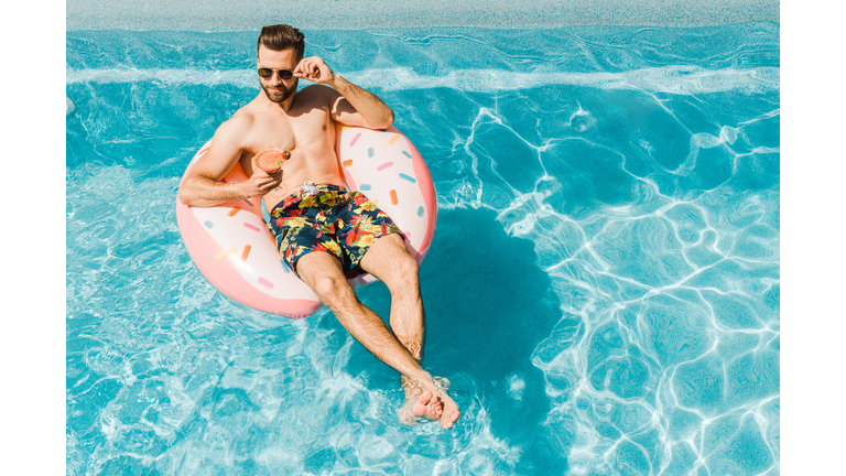 overhead view of handsome man touching sunglasses and holding cocktail glass