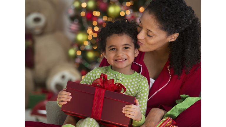 Mixed race mother and daughter opening Christmas present