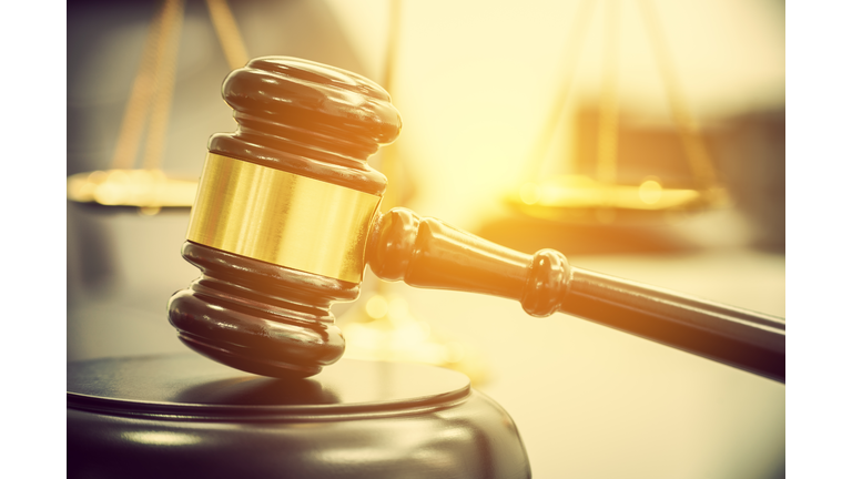 Legal office of lawyers, justice and law concept : Wooden judge gavel or a wood hammer and a soundboard used by a judge person on a desk in a courtroom with a blurred brass scale of justice behind.