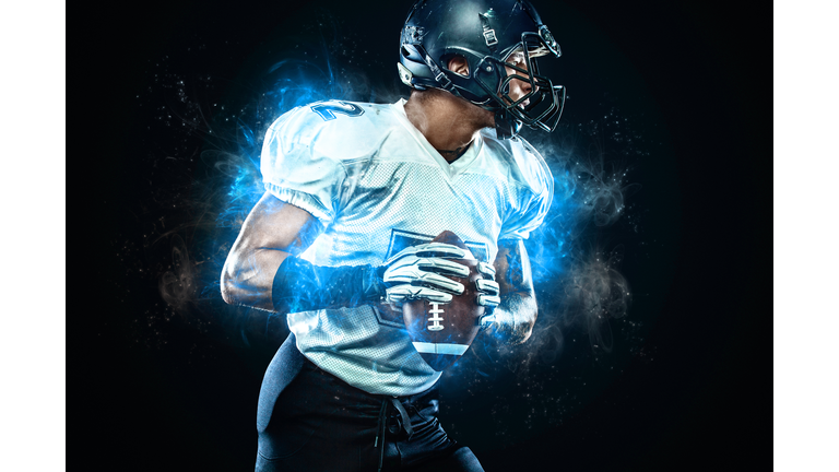 American football player in helmet with ball in hands. Fire background. Team sports. Sport wallpaper.