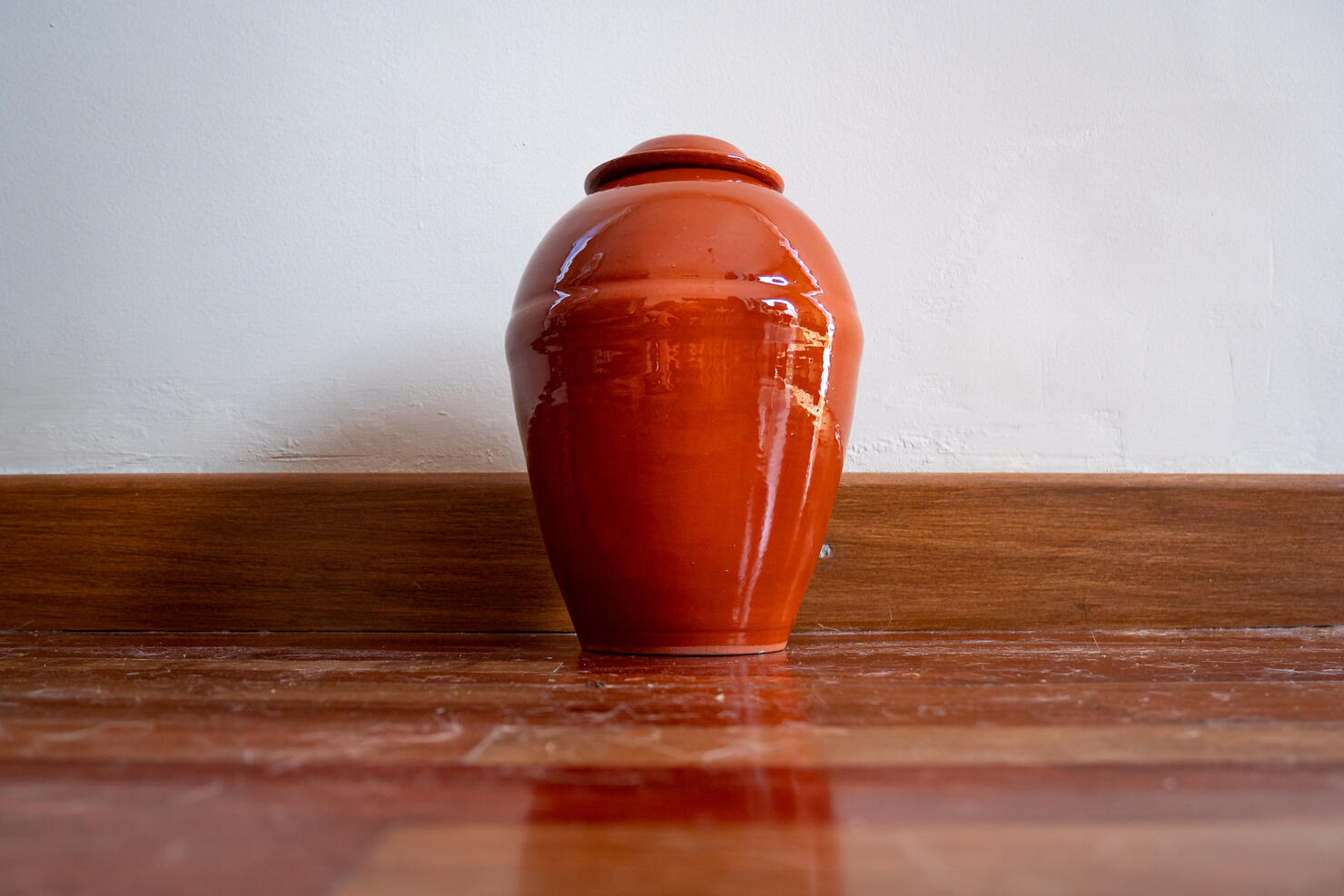 Orange Urn Leaning Against the White Wall