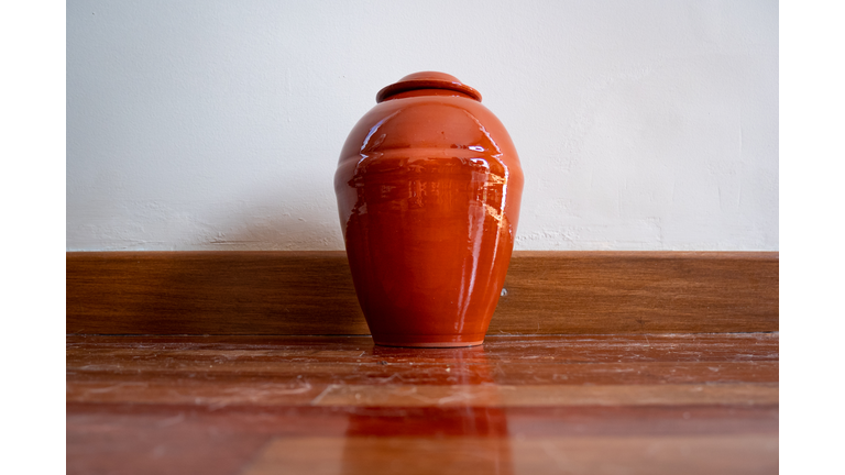 Orange Urn Leaning Against the White Wall