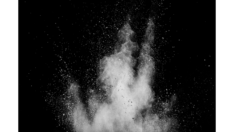 White powder explosion isolated on black background. White dust particles splash.Color Holi Festival.